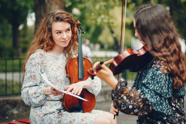 Meninas bonitas e românticas em um parque com um violino — Fotografia de Stock