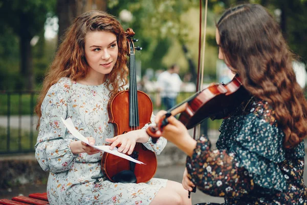 Meninas bonitas e românticas em um parque com um violino — Fotografia de Stock