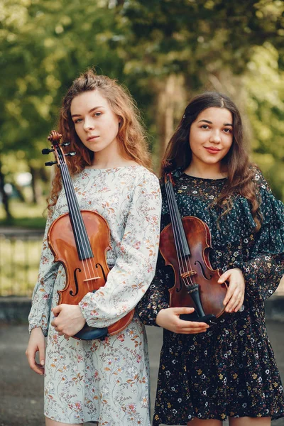 Meninas bonitas e românticas em um parque com um violino — Fotografia de Stock