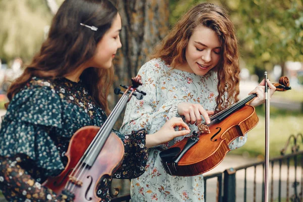 Belle e romantiche ragazze in un parco con un violino — Foto Stock