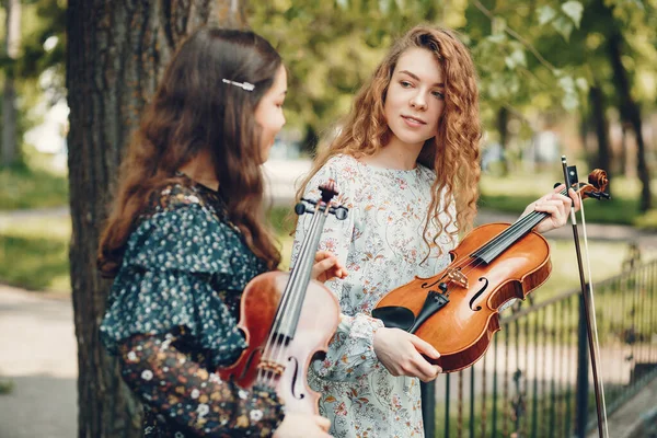 Belle e romantiche ragazze in un parco con un violino — Foto Stock