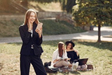 Öğrenciler arka planda kitaplarla çimlerin üzerinde yatıyorlar.