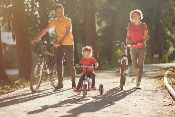 Семья с велосипедом в летнем парке

