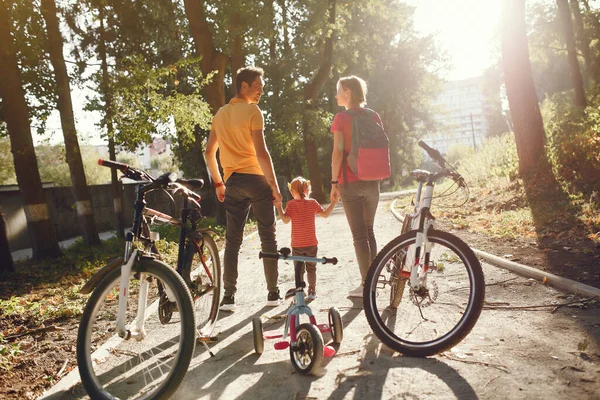 Family with a bicycle in a summer park — Stock Photo, Image
