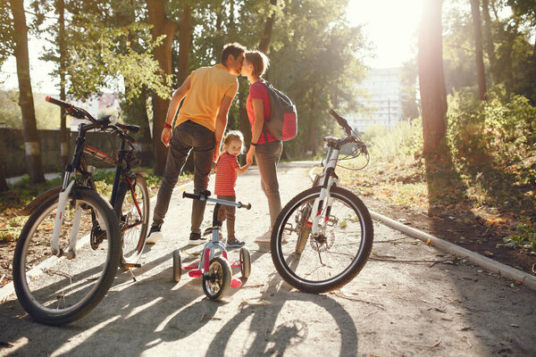 Семья с велосипедом в летнем парке
