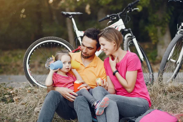 Família com uma bicicleta em um parque de verão — Fotografia de Stock