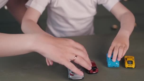 Madre e hijo jugando con coches de juguete en la mesa — Vídeos de Stock