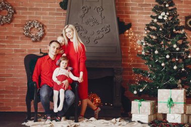 Aile Noel ağacının yanında oturuyor.