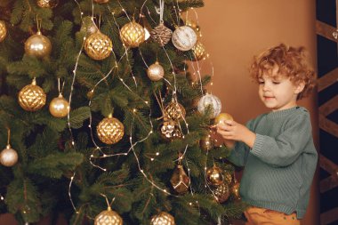 Gri kazaklı küçük çocuk Noel ağacının yanında