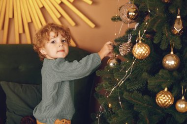 Gri kazaklı küçük çocuk Noel ağacının yanında