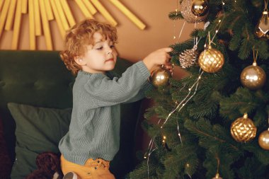 Gri kazaklı küçük çocuk Noel ağacının yanında