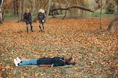 Sonbahar parkında iki oğlan Afrikalı bir kıza yardım ediyor.
