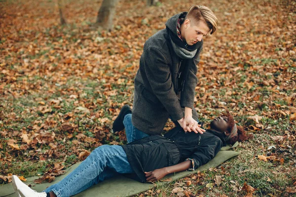 L'uomo in un parco autunnale aiuta la ragazza africana — Foto Stock