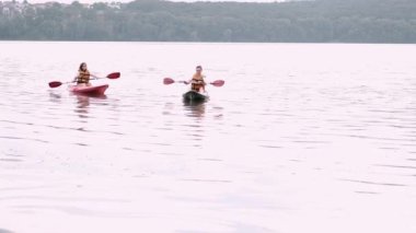 İki kadın arkadaş gölde kayak yapıyor.