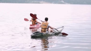 İki kadın arkadaş gölde kayak yapıyor.