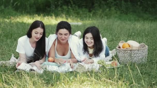 Τρία όμορφα κορίτσια κείτονται στο γρασίδι με βιβλία. — Αρχείο Βίντεο