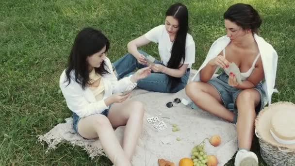 Grupo de meninas amigas fazendo piquenique ao ar livre e jogando um jogo de cartas — Vídeo de Stock