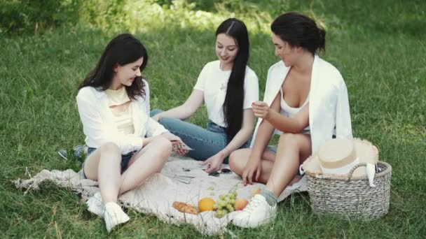 Grupo de amigas haciendo picnic al aire libre y jugando un juego de cartas — Vídeos de Stock
