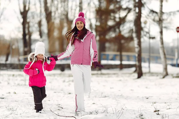 Мать и ребенок в зимней одежде играют в зимнем парке — стоковое фото