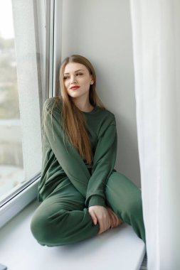 Evdeki pencere pervazında oturan kadın.