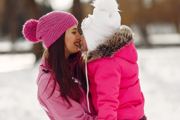 Madre e bambino in abiti invernali giocano nel parco invernale — Foto Stock