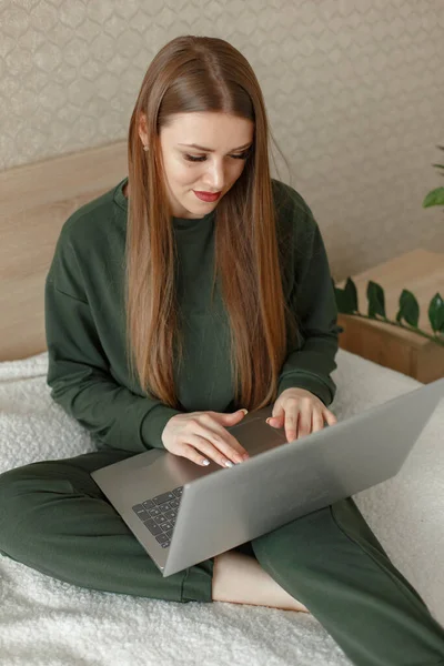 Femeia care stă pe un pat și folosește un laptop — Fotografie, imagine de stoc