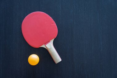 Kırmızı Masa Tenisi Raketi ve Siyah Tahta Masa Üzerinde Sarı Top