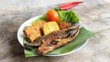 Domates soslu ve taze sebzeli bir tabak kızarmış yayın balığı geleneksel Endonezya mutfağıdır. catfish pecel, menü katalogları, yemek tarifi dergileri ve kapaklar için uygun