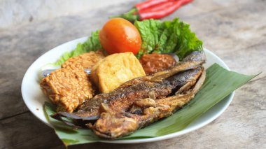Domates soslu ve taze sebzeli bir tabak kızarmış yayın balığı geleneksel Endonezya mutfağıdır. catfish pecel, menü katalogları, yemek tarifi dergileri ve kapaklar için uygun