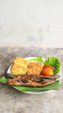 Domates soslu ve taze sebzeli bir tabak kızarmış yayın balığı geleneksel Endonezya mutfağıdır. catfish pecel, menü katalogları, yemek tarifi dergileri ve kapaklar için uygun