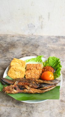 Domates soslu ve taze sebzeli bir tabak kızarmış yayın balığı geleneksel Endonezya mutfağıdır. catfish pecel, menü katalogları, yemek tarifi dergileri ve kapaklar için uygun