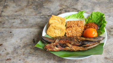 Domates soslu ve taze sebzeli bir tabak kızarmış yayın balığı geleneksel Endonezya mutfağıdır. catfish pecel, menü katalogları, yemek tarifi dergileri ve kapaklar için uygun