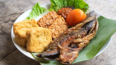 Domates soslu ve taze sebzeli bir tabak kızarmış yayın balığı geleneksel Endonezya mutfağıdır. catfish pecel, menü katalogları, yemek tarifi dergileri ve kapaklar için uygun