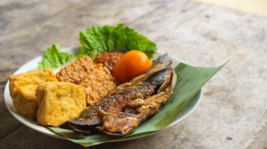 Domates soslu ve taze sebzeli bir tabak kızarmış yayın balığı geleneksel Endonezya mutfağıdır. catfish pecel, menü katalogları, yemek tarifi dergileri ve kapaklar için uygun