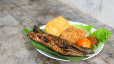 Domates soslu ve taze sebzeli bir tabak kızarmış yayın balığı geleneksel Endonezya mutfağıdır. catfish pecel, menü katalogları, yemek tarifi dergileri ve kapaklar için uygun