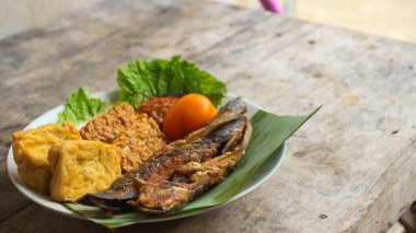Domates soslu ve taze sebzeli bir tabak kızarmış yayın balığı geleneksel Endonezya mutfağıdır. catfish pecel, menü katalogları, yemek tarifi dergileri ve kapaklar için uygun
