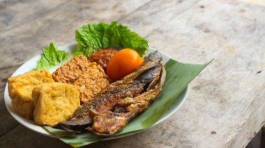 Domates soslu ve taze sebzeli bir tabak kızarmış yayın balığı geleneksel Endonezya mutfağıdır. catfish pecel, menü katalogları, yemek tarifi dergileri ve kapaklar için uygun