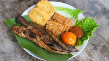 Domates soslu ve taze sebzeli bir tabak kızarmış yayın balığı geleneksel Endonezya mutfağıdır. catfish pecel, menü katalogları, yemek tarifi dergileri ve kapaklar için uygun