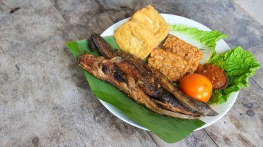 Domates soslu ve taze sebzeli bir tabak kızarmış yayın balığı geleneksel Endonezya mutfağıdır. catfish pecel, menü katalogları, yemek tarifi dergileri ve kapaklar için uygun