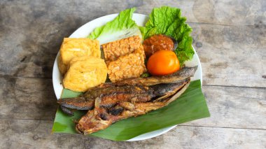 Domates soslu ve taze sebzeli bir tabak kızarmış yayın balığı geleneksel Endonezya mutfağıdır. catfish pecel, menü katalogları, yemek tarifi dergileri ve kapaklar için uygun