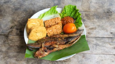 Domates soslu ve taze sebzeli bir tabak kızarmış yayın balığı geleneksel Endonezya mutfağıdır. catfish pecel, menü katalogları, yemek tarifi dergileri ve kapaklar için uygun