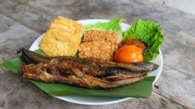 Domates soslu ve taze sebzeli bir tabak kızarmış yayın balığı geleneksel Endonezya mutfağıdır. catfish pecel, menü katalogları, yemek tarifi dergileri ve kapaklar için uygun