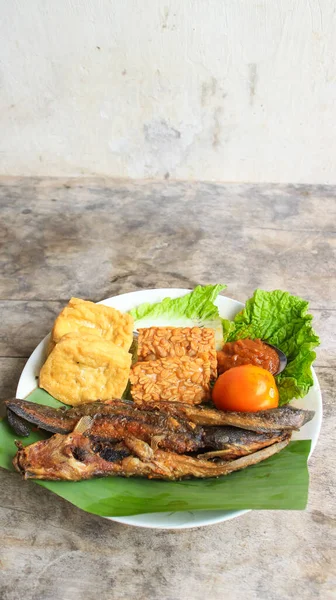 Domates soslu ve taze sebzeli bir tabak kızarmış yayın balığı geleneksel Endonezya mutfağıdır. catfish pecel, menü katalogları, yemek tarifi dergileri ve kapaklar için uygun