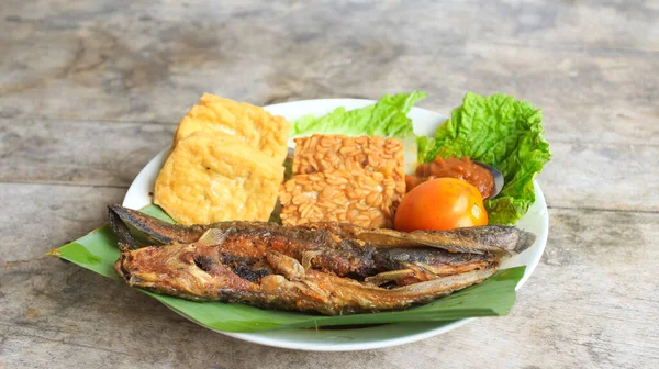 Domates soslu ve taze sebzeli bir tabak kızarmış yayın balığı geleneksel Endonezya mutfağıdır. catfish pecel, menü katalogları, yemek tarifi dergileri ve kapaklar için uygun