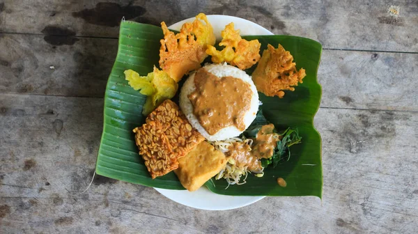 Yalnız bir tabak pecel pilavı. Menü katalogları için uygun. Nasi pecel veya sega pecel, Endonezya 'nın tipik bir pirinç yemeğidir. Ceviz biber sosu ve salata gibi sebzelerle servis edilir..