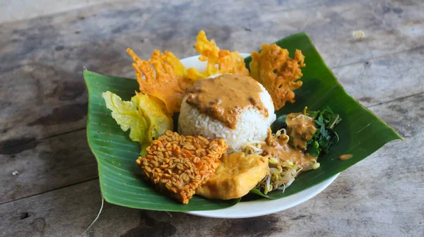 Yalnız bir tabak pecel pilavı. Menü katalogları için uygun. Nasi pecel veya sega pecel, Endonezya 'nın tipik bir pirinç yemeğidir. Ceviz biber sosu ve salata gibi sebzelerle servis edilir..