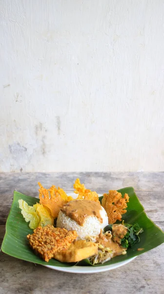 Yalnız bir tabak pecel pilavı. Menü katalogları için uygun. Nasi pecel veya sega pecel, Endonezya 'nın tipik bir pirinç yemeğidir. Ceviz biber sosu ve salata gibi sebzelerle servis edilir..