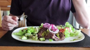 Bir adam bir restoranda bir salata ve bir biftek yiyor.