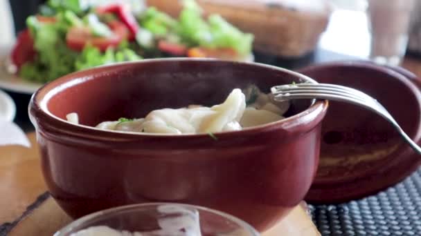 Knödel in einem Tontopf. Heißes Essen mit Dampf. — Stockvideo