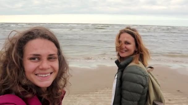 Dos mujeres jóvenes caminan por la playa y se toman selfie . — Vídeo de stock